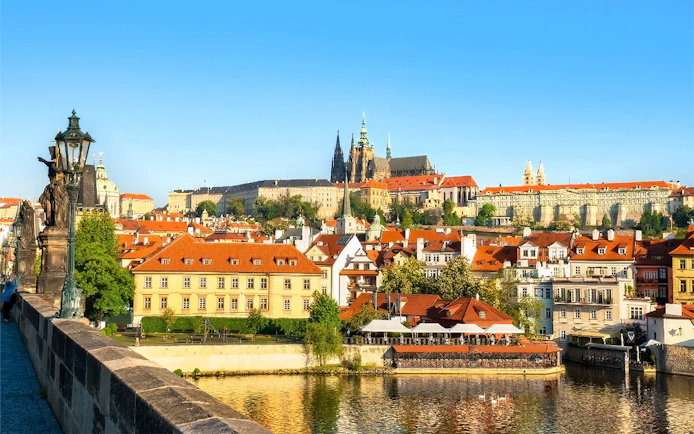 Prague Castle complex viewed from across the Vltava River on a sunny day.