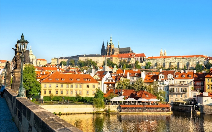 Prague Castle complex viewed from across the Vltava River on a sunny day.