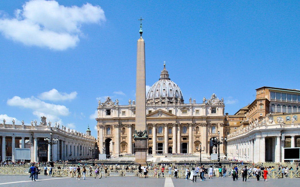 St. Peter's Basilica with obelisk in Vatican City, Rome, surrounded by tourists.