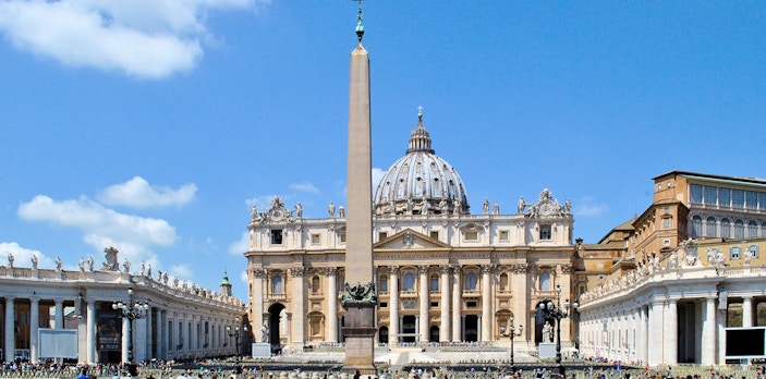 St. Peter's Basilica with obelisk in Vatican City, Rome, surrounded by tourists.