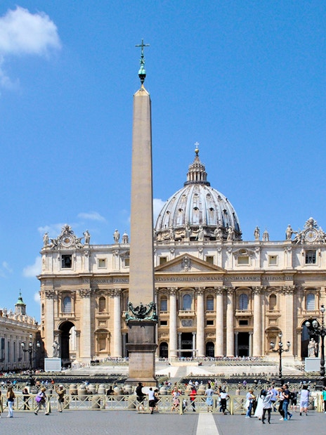 St. Peter's Basilica with obelisk in Vatican City, Rome, surrounded by tourists.