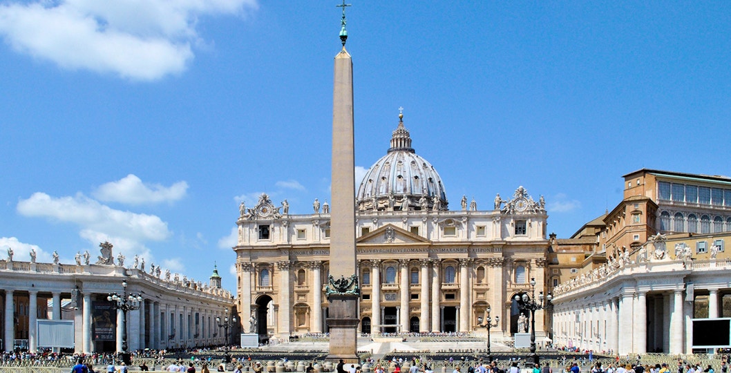 St. Peter's Basilica with obelisk in Vatican City, Rome, surrounded by tourists.