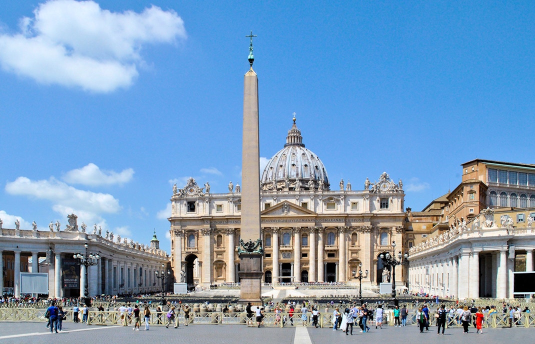 St. Peter's Basilica with obelisk in Vatican City, Rome, surrounded by tourists.