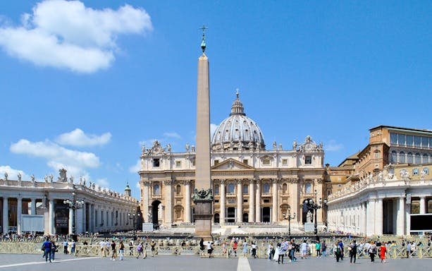 St. Peter's Basilica with obelisk in Vatican City, Rome, surrounded by tourists.