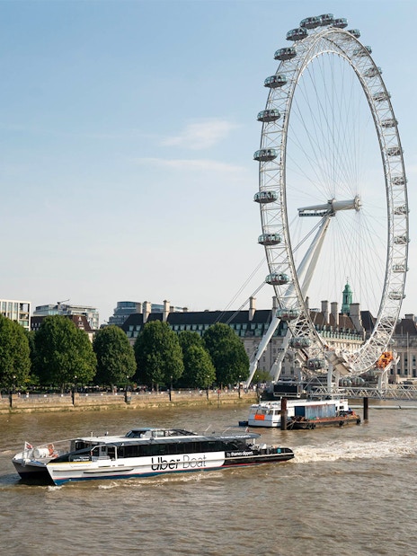 London Eye and river cruise boat on the Thames River.