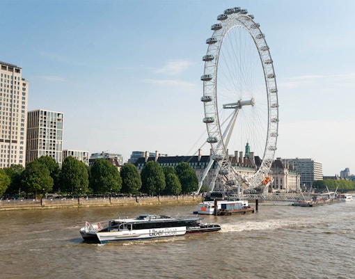 London Eye and river cruise boat on the Thames River.