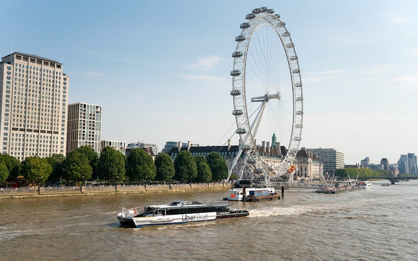 London Eye and river cruise boat on the Thames River.