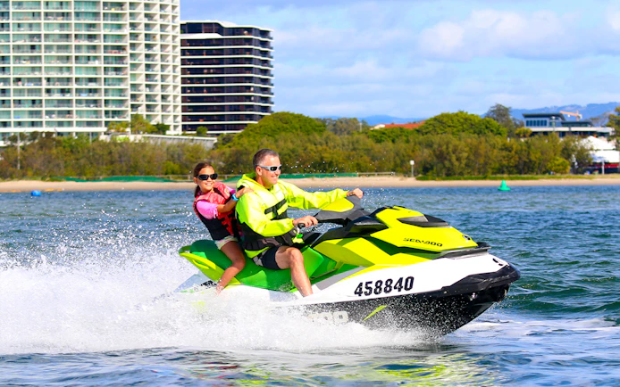 Jet skiing near city waterfront during Jet Ski & Parasail Experience.