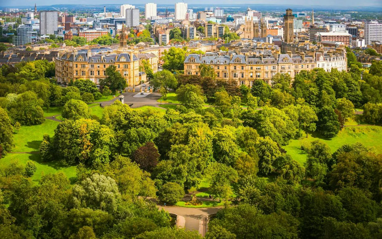 Aerial view of Glasgow cityscape with historic buildings and lush greenery, part of a self-guided exploration game.