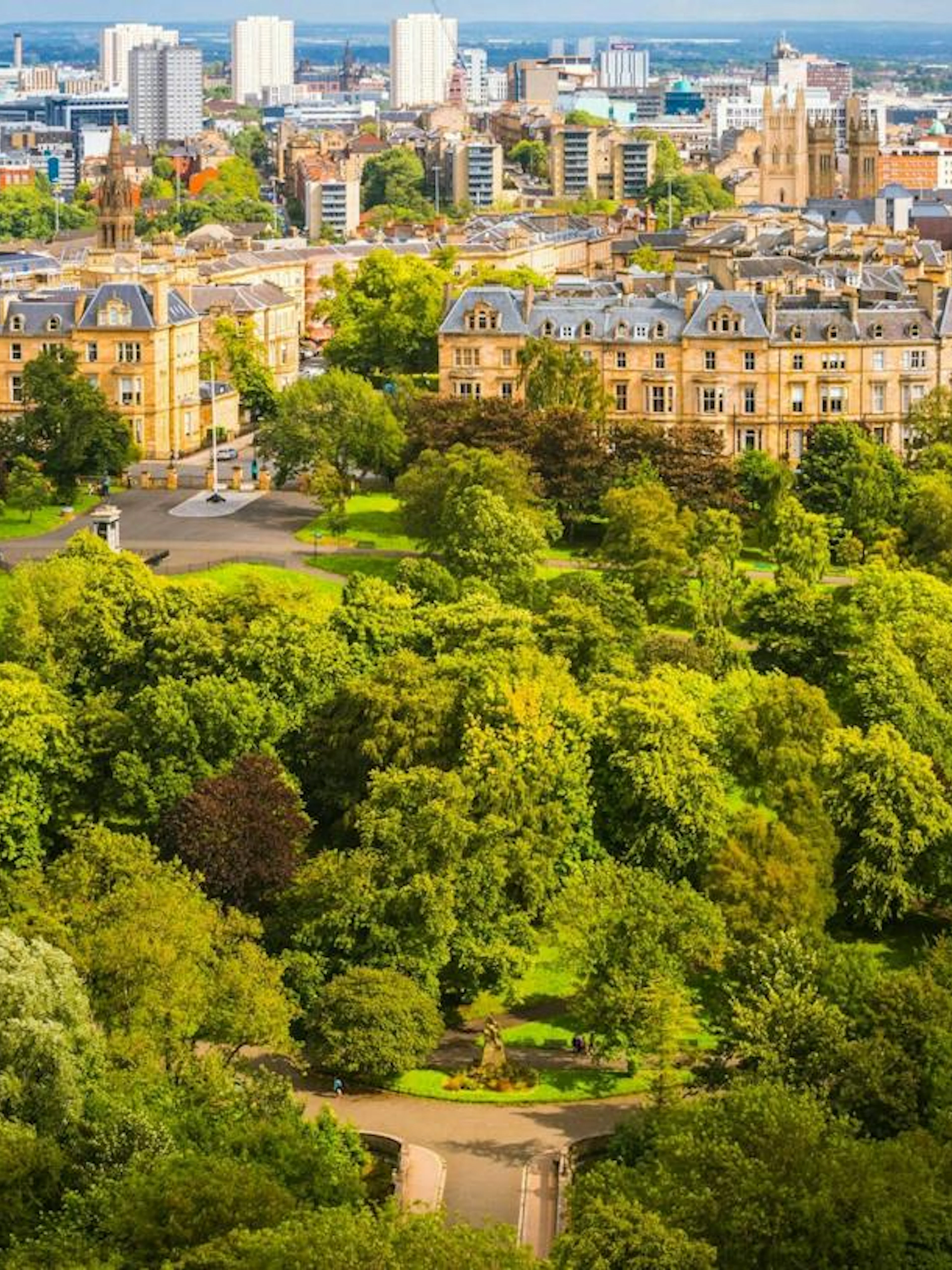 Aerial view of Glasgow cityscape with historic buildings and lush greenery, part of a self-guided exploration game.