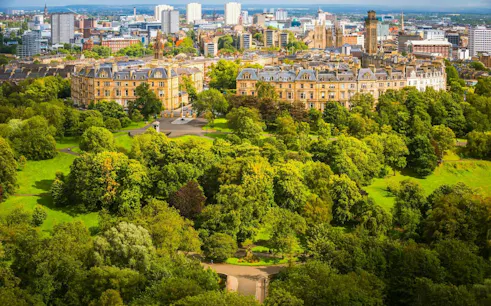 Aerial view of Glasgow cityscape with historic buildings and lush greenery, part of a self-guided exploration game.