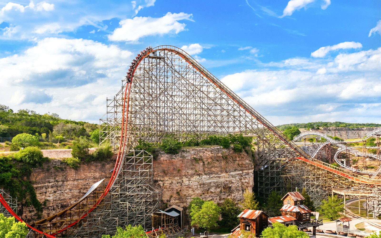 Roller coaster Iron Rattler at Six Flags Fiesta Texas with steep drop and scenic backdrop.