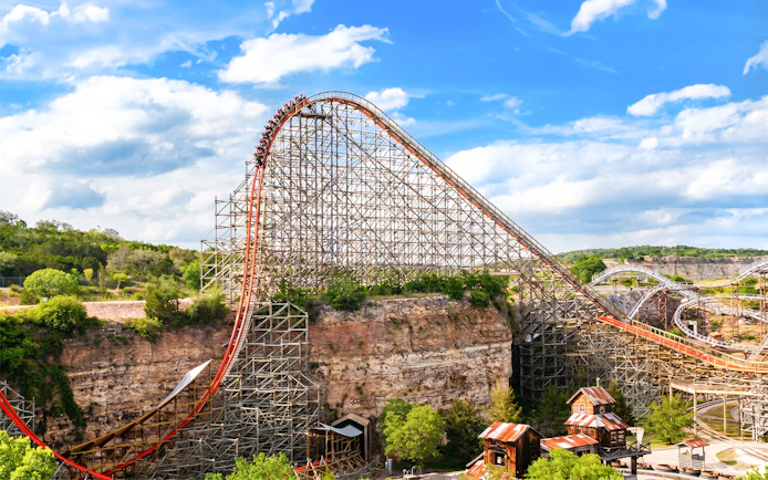 Roller coaster Iron Rattler at Six Flags Fiesta Texas with steep drop and scenic backdrop.