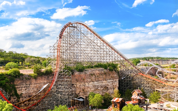 Roller coaster Iron Rattler at Six Flags Fiesta Texas with steep drop and scenic backdrop.