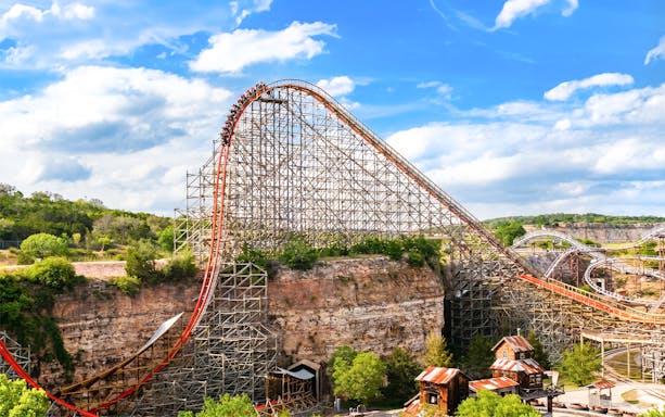 Roller coaster Iron Rattler at Six Flags Fiesta Texas with steep drop and scenic backdrop.