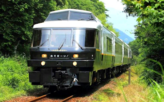 Train traveling through lush greenery in Kyushu, Japan, part of the JR PASS rail network.