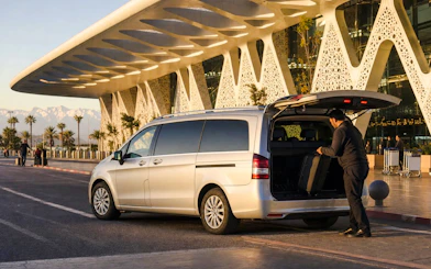Private transfer service at Marrakech Airport with a driver loading luggage into a van.