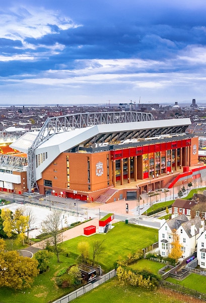 Liverpool FC stadium aerial view, showcasing the iconic red exterior and surrounding cityscape.