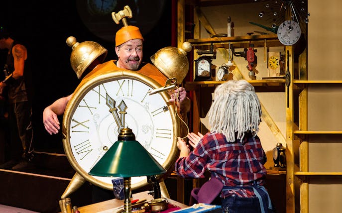 Man in clock costume interacting with child character in "Peter and Anneli's Journey to the Moon" play.