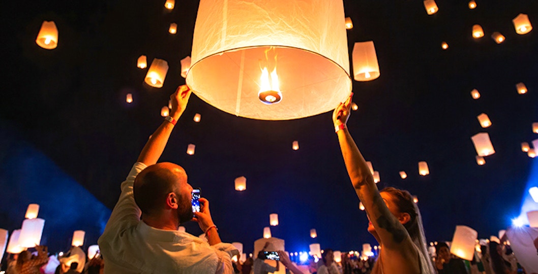 Couple releasing paper lantern at night in Chiang Mai, Thailand.