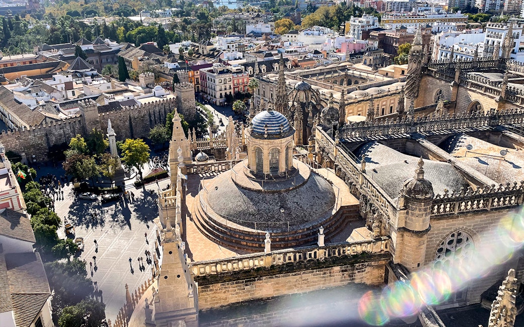 Aerial view of Seville Cathedral and Giralda tower with surrounding cityscape.