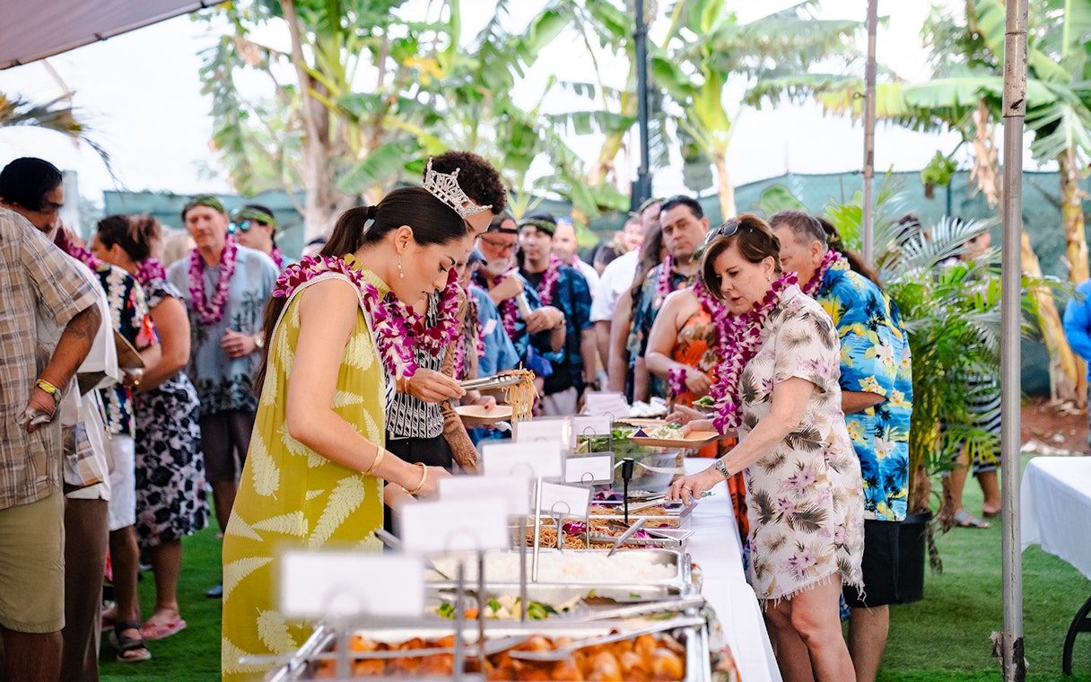 Guests serving themselves at a buffet of Polynesian food at Mauka Warriors Luau.