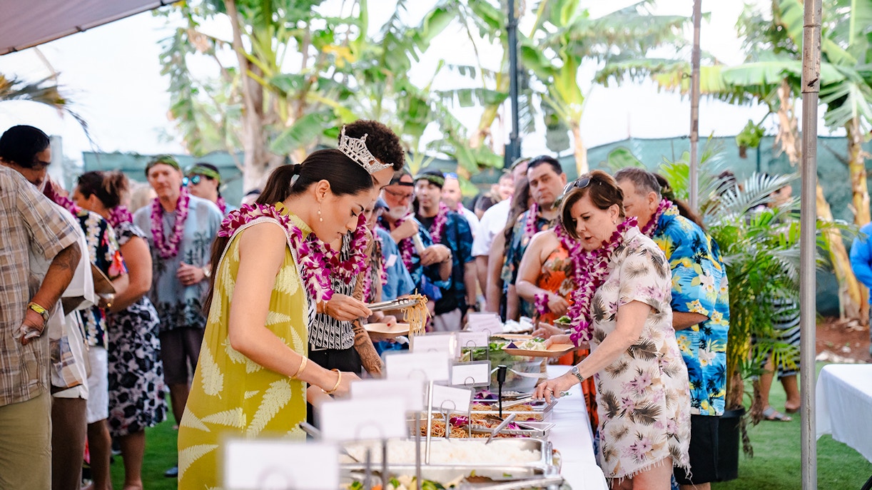 Guests serving themselves at a buffet of Polynesian food at Mauka Warriors Luau.