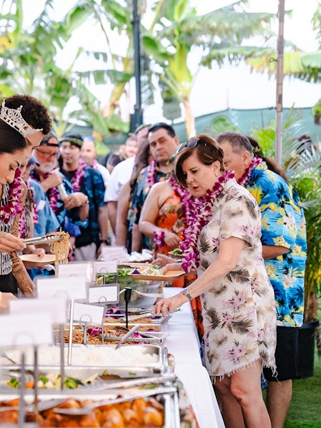 Guests serving themselves at a buffet of Polynesian food at Mauka Warriors Luau.