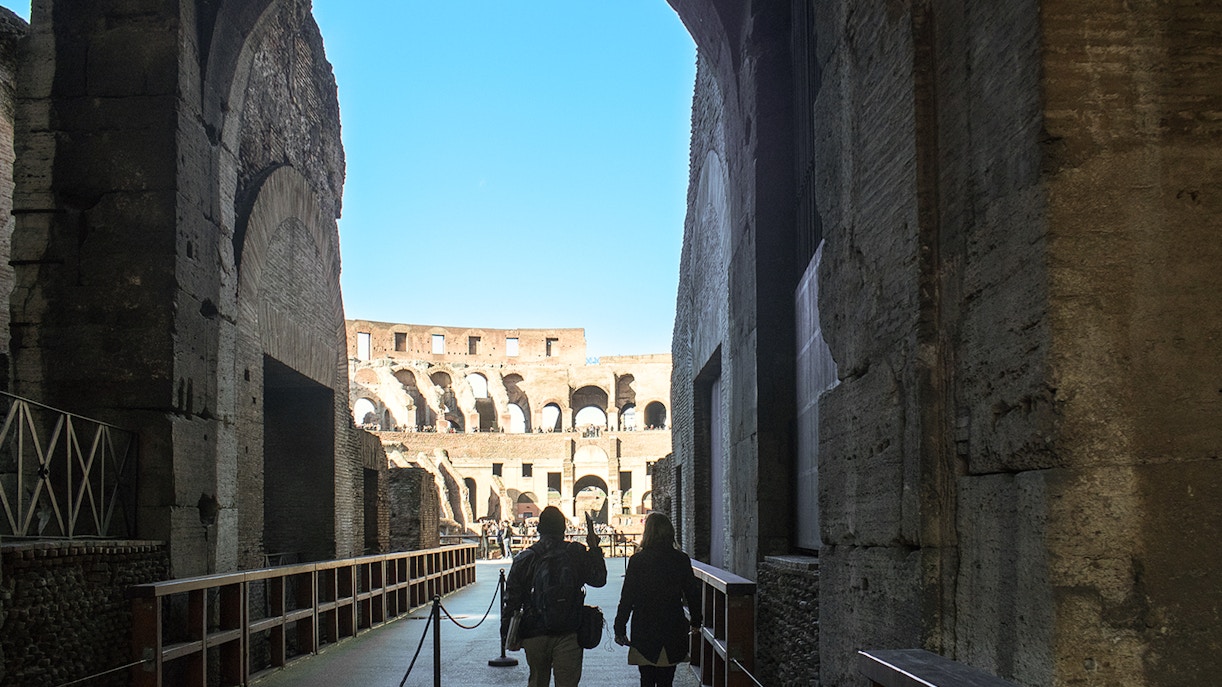 Visitors walking through the Colosseum's interior passageway in Rome.