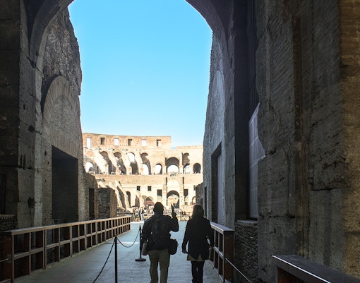 Visitors walking through the Colosseum's interior passageway in Rome.