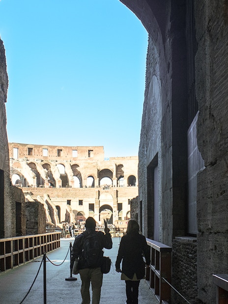 Visitors walking through the Colosseum's interior passageway in Rome.