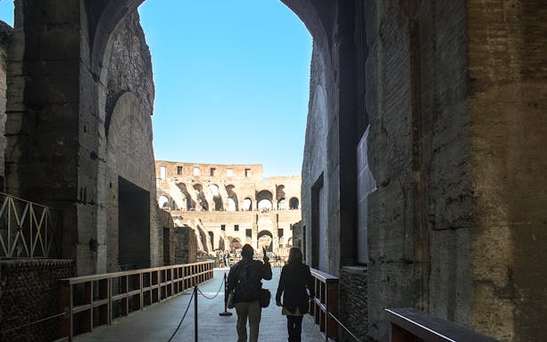 Visitors walking through the Colosseum's interior passageway in Rome.