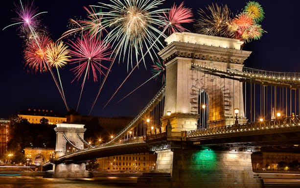 Chain Bridge in Budapest with fireworks in the night sky.