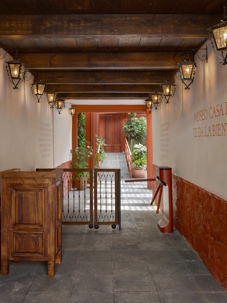 Entrance hallway of Museo Casa Kahlo with wooden beams and lanterns.