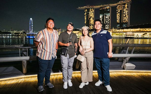 Group enjoying Singapore night tour with Marina Bay Sands and Singapore Flyer in the background.