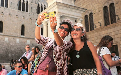 Tourists taking a selfie in front of a historic building in Siena, Italy.
