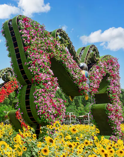 Dubai Butterfly Garden floral sculpture with vibrant flowers and sunflowers in foreground.