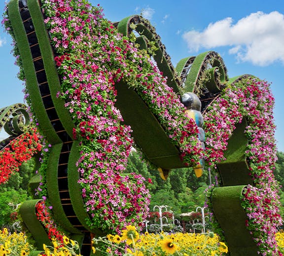 Dubai Butterfly Garden floral sculpture with vibrant flowers and sunflowers in foreground.