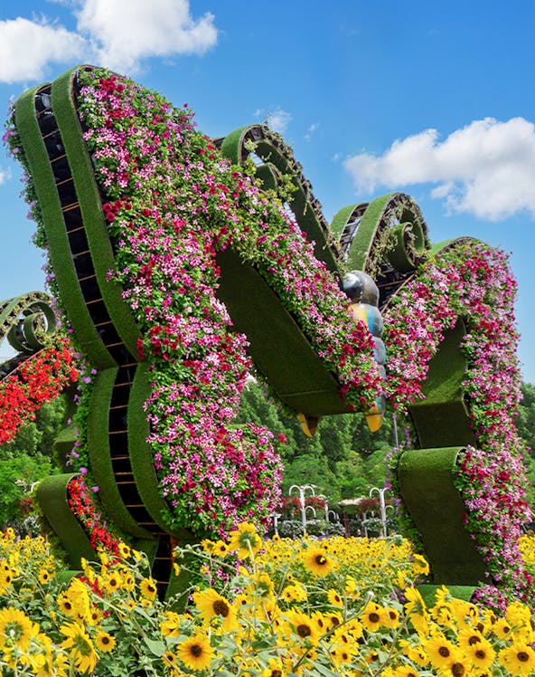 Dubai Butterfly Garden floral sculpture with vibrant flowers and sunflowers in foreground.