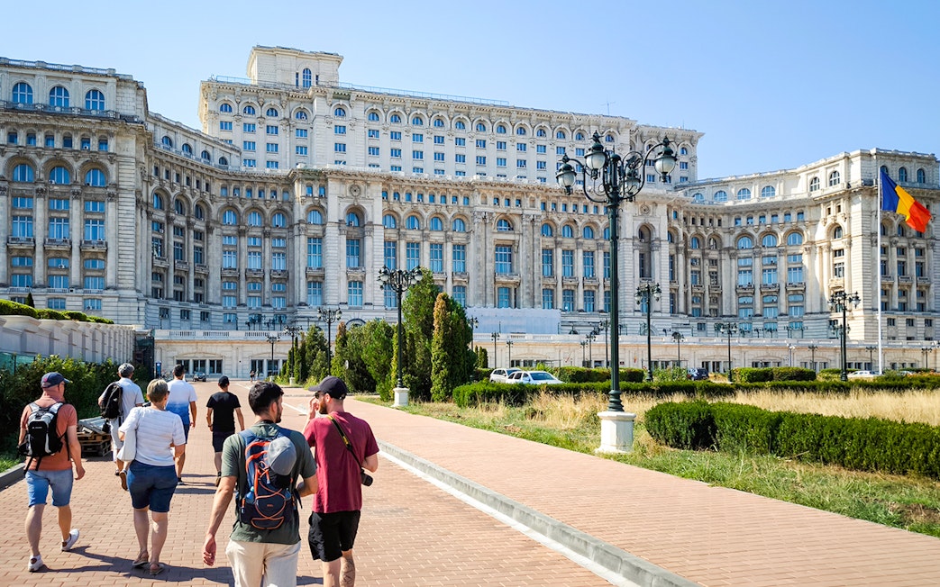 Visitors walking outside the Palace of Parliament in Bucharest, Romania.