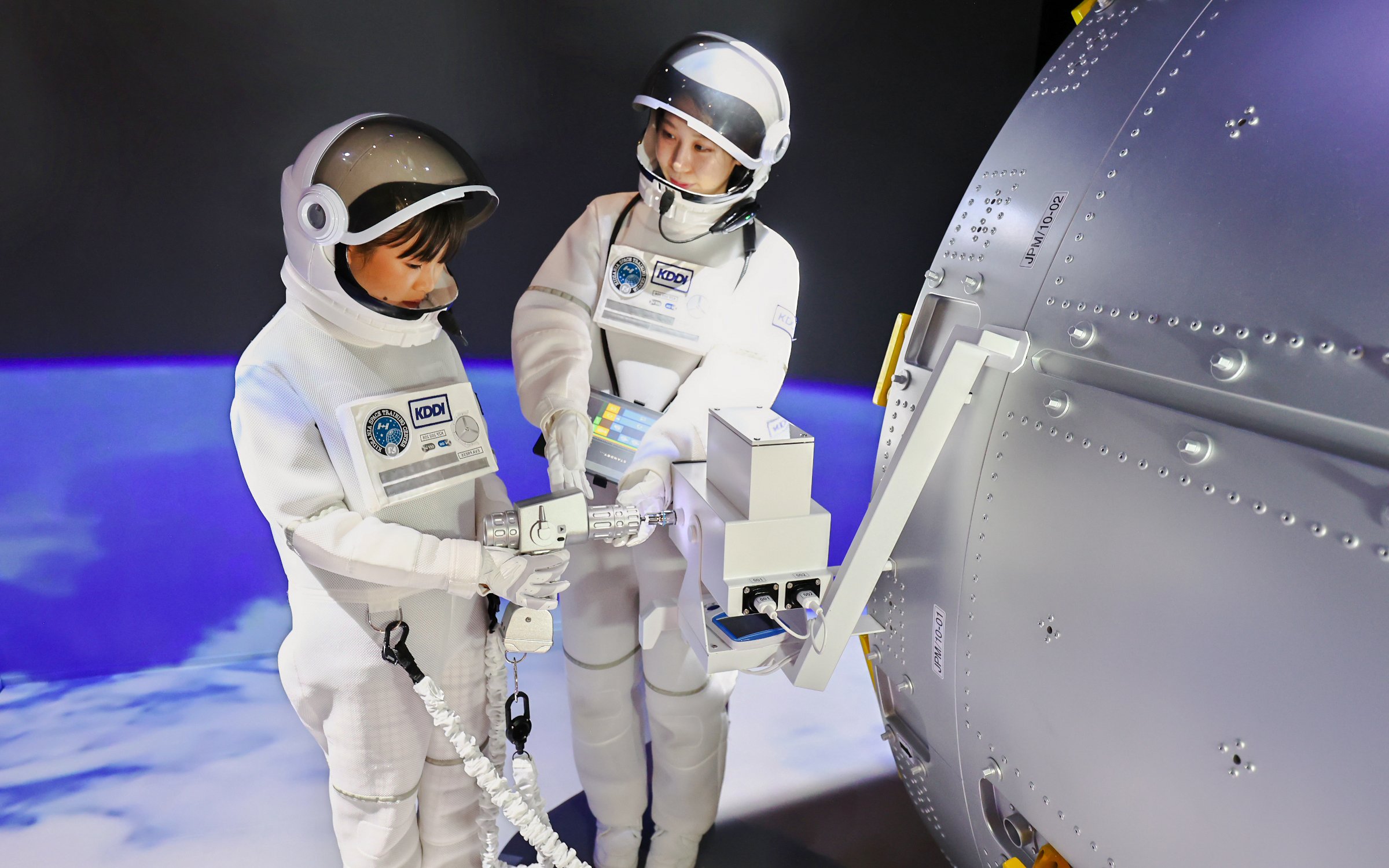 Children in astronaut suits interacting with a spaceship module at KidZania Fukuoka.