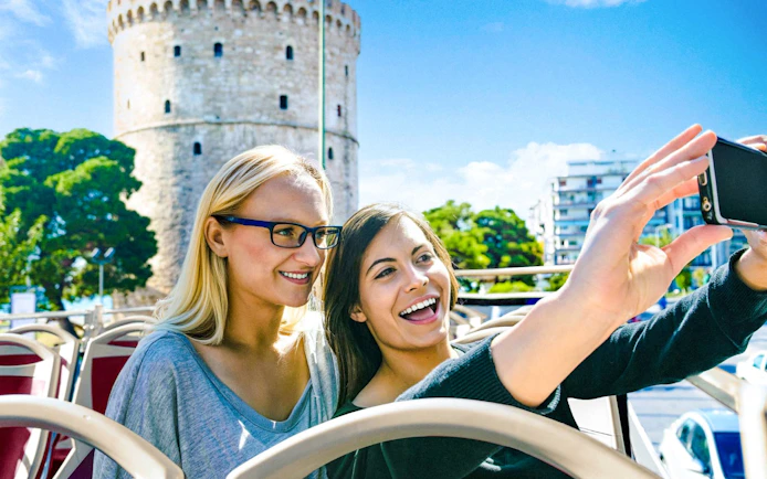 Guests taking a selfie on Big Bus Tour with White Tower in Thessaloniki, Greece.