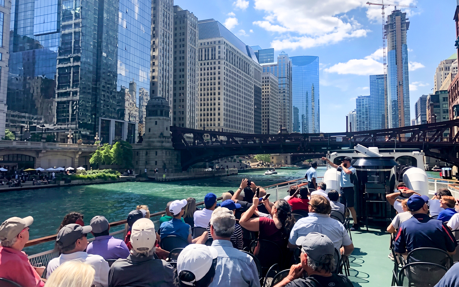Sightseeing cruise on Chicago River with view of city skyline and bridge.