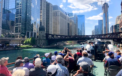 Sightseeing cruise on Chicago River with view of city skyline and bridge.
