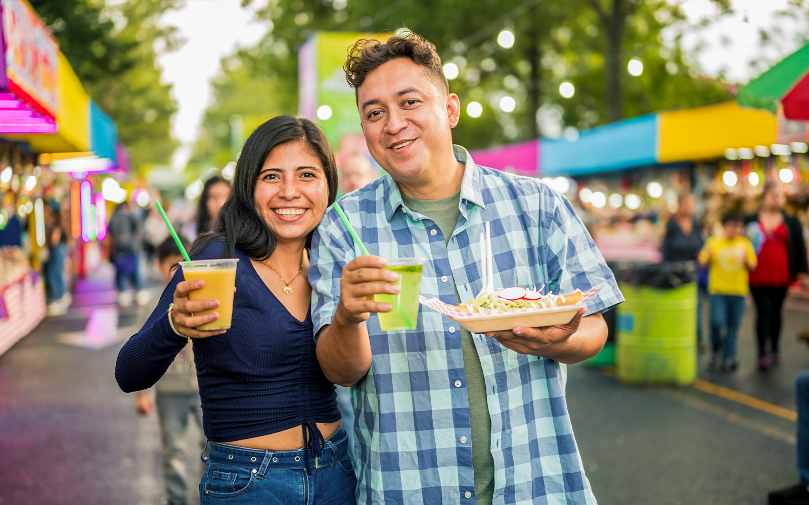 Couple enjoying drinks and street food at a vibrant outdoor market.