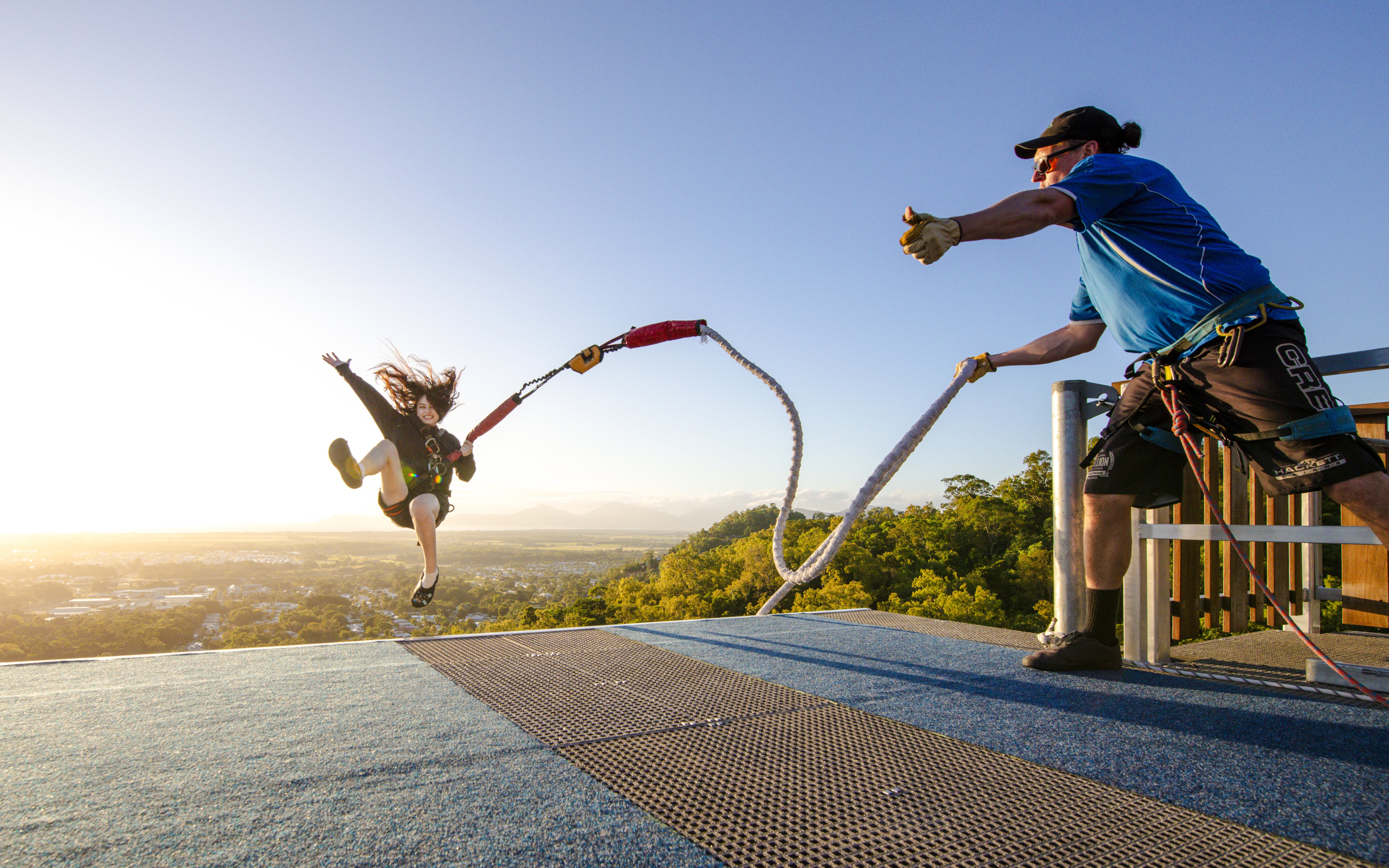 Person jumping off platform during Walk The Plank by AJ Hackett with scenic view in background.