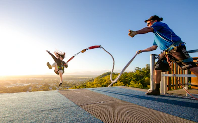 Person bungee jumping from a rooftop platform with a scenic view in the background.
