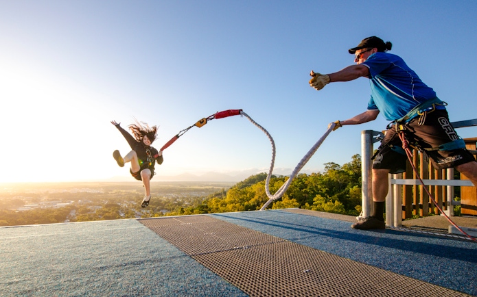 Person bungee jumping from a rooftop platform with a scenic view in the background.