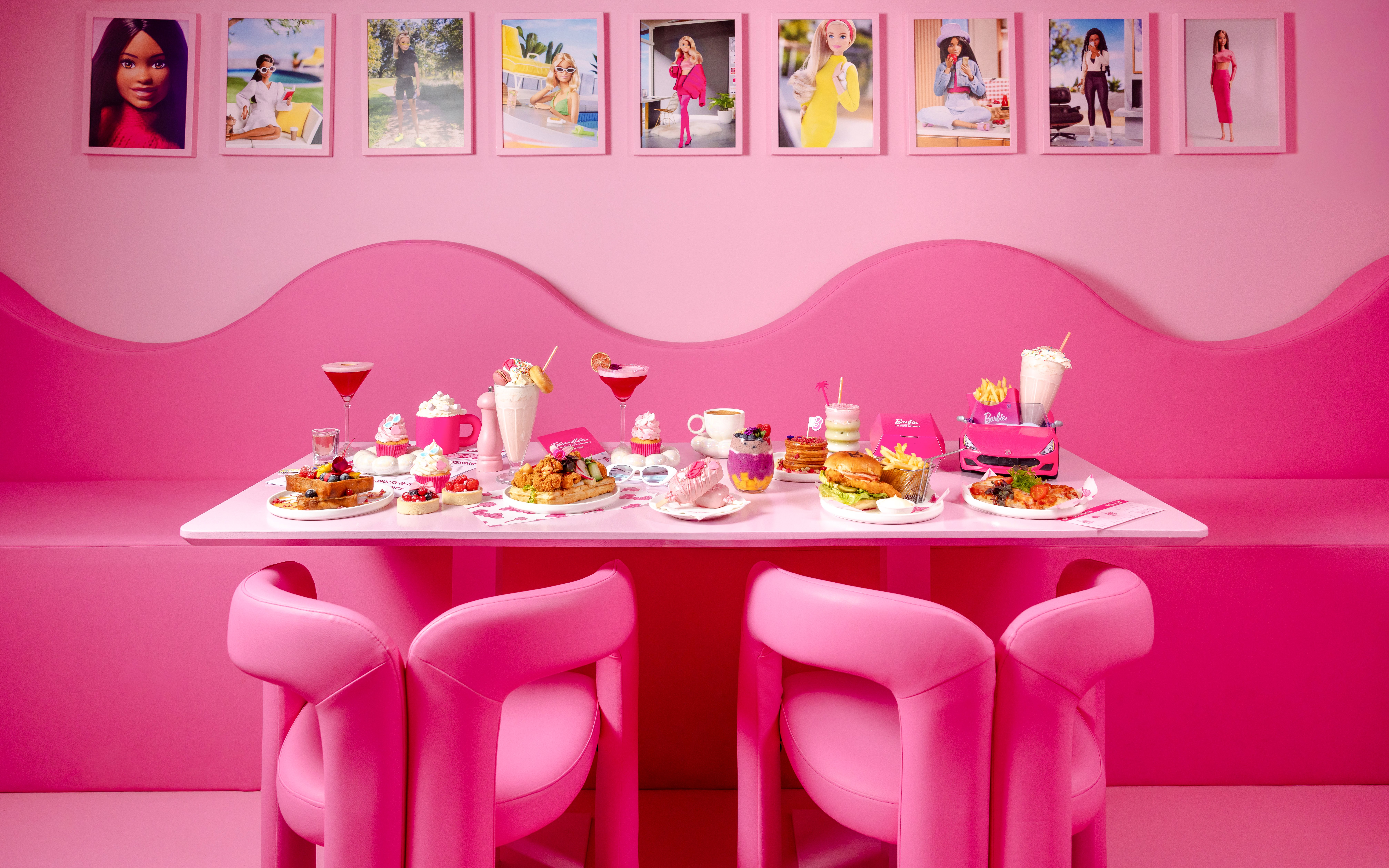 Pink-themed cafe table with assorted desserts and drinks at Barbie, The Dream Experience.
