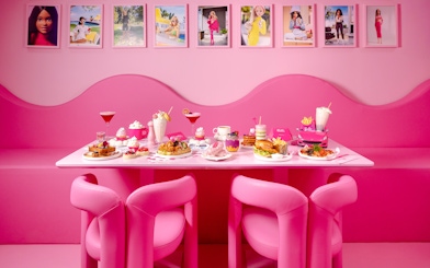 Pink-themed cafe table with assorted desserts and drinks at Barbie, The Dream Experience.